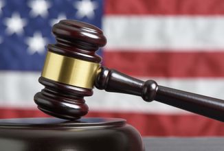 close-up-of-wooden-judge-gavel-american-flag-in-b-2023-01-06-08-43-57-utc.jpg